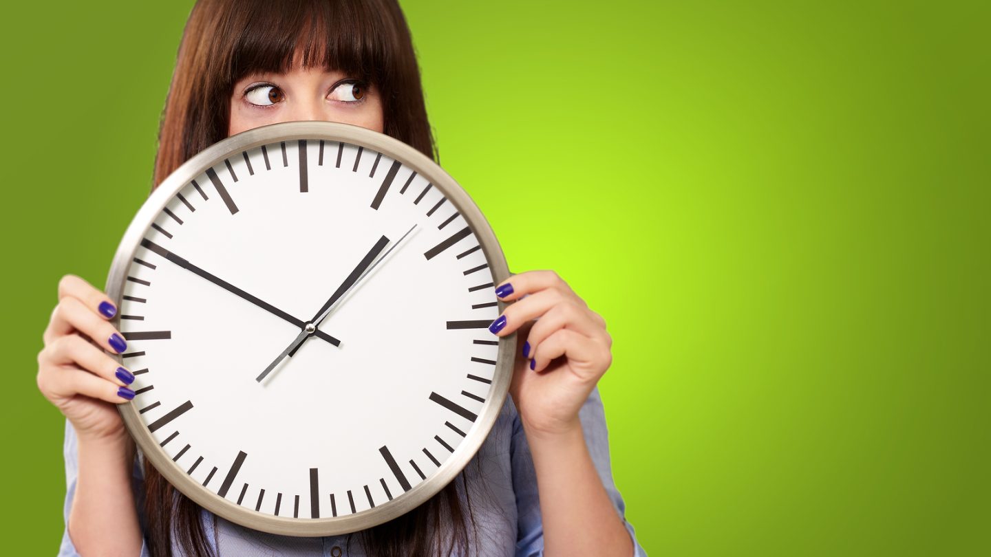 A Young Girl Holding A Clock On Green Background